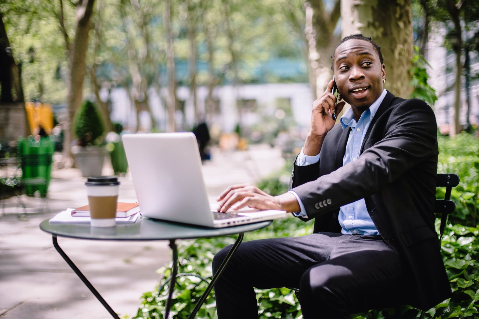 Young African entrepreneur working on laptop at street cafe